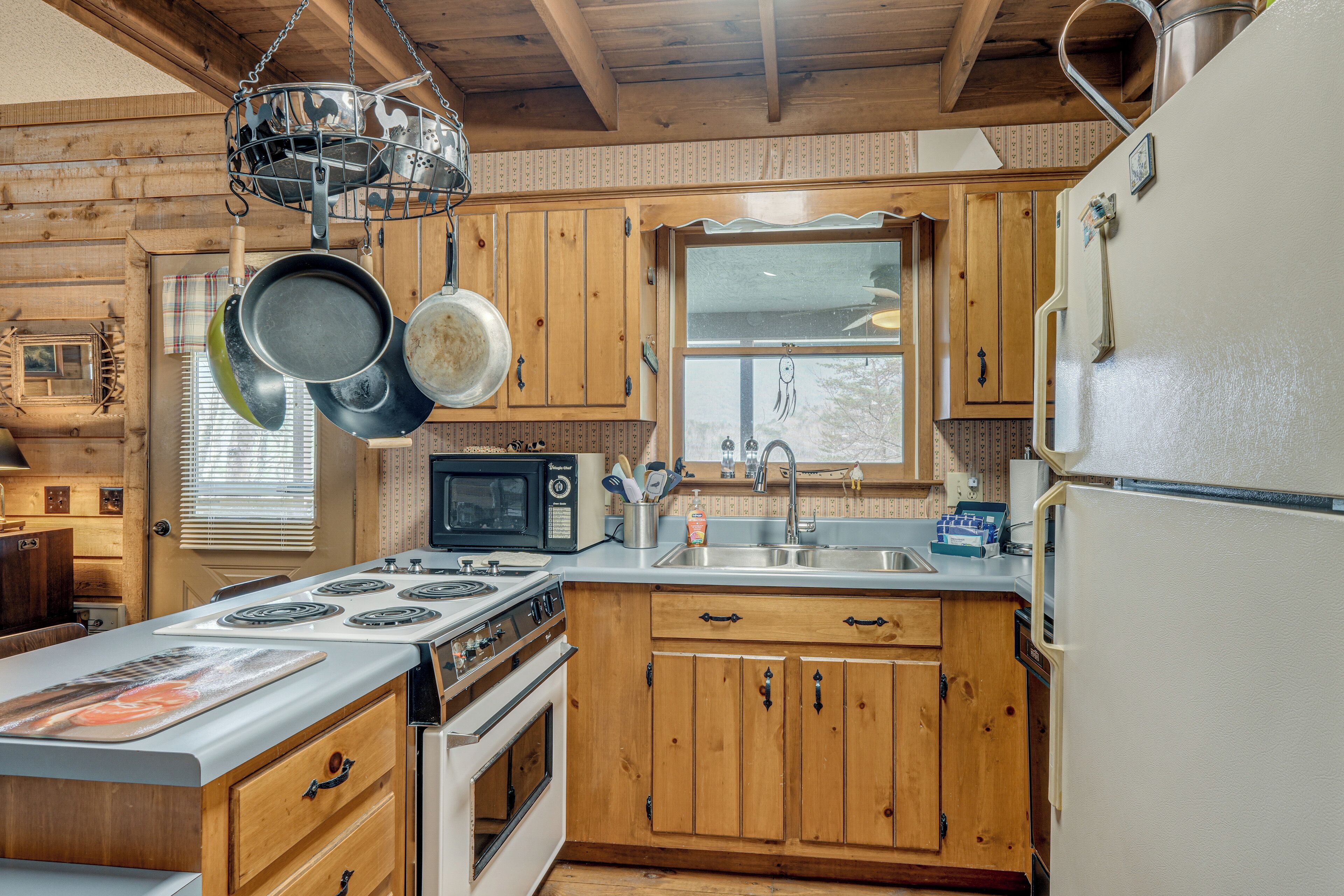Una cocina con armarios de madera, estufa, microondas y refrigerador.