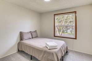 A bedroom with a single bed, a window with a view of trees and a house, and a carpeted floor. - Quiet Eugene Retreat Near Mount Pisgah & UO Campus (Eugene)
