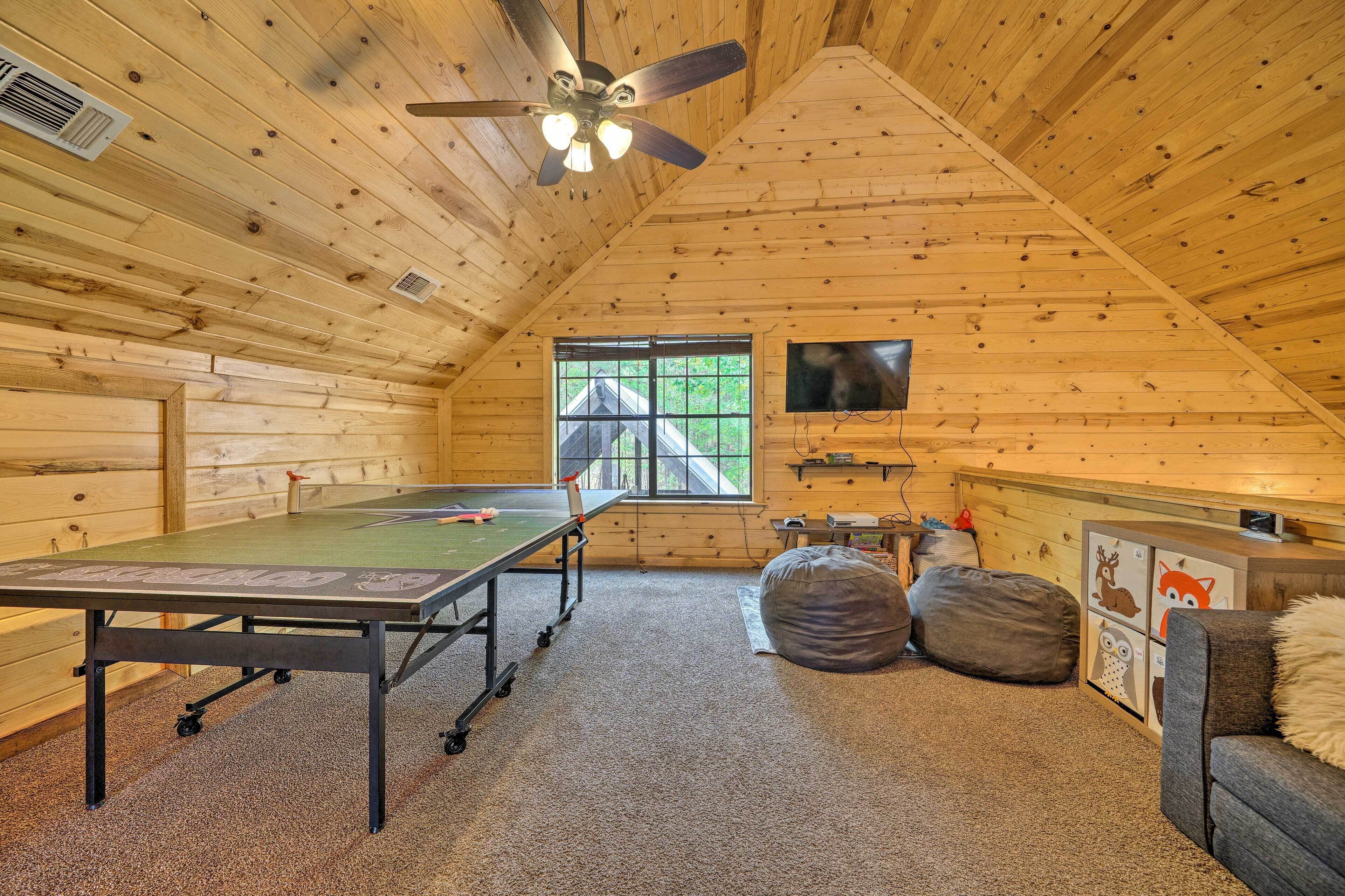 A wooden cabin with a ping pong table, bean bags, and a television on the wall.