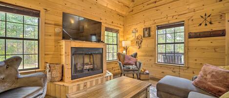 A cozy cabin interior with a fireplace, wooden walls, and a comfortable seating area.