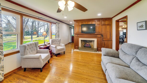 Una sala de estar con chimenea, televisor y ventanas amplias.