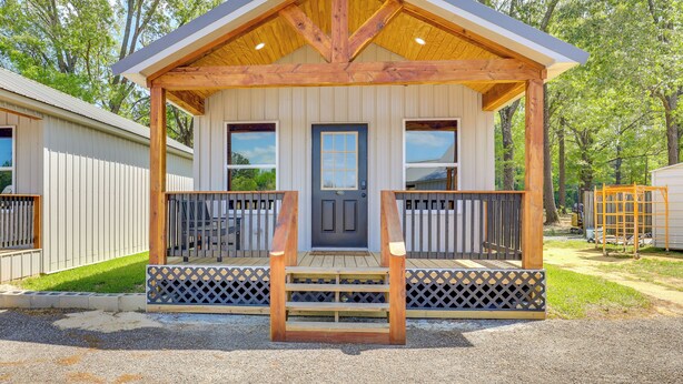 A wooden cabin with a porch, a front door, and a small window.