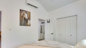 A bedroom with a bed, a door, a coat rack, and a painting on the wall.