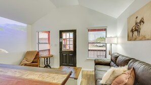 A living room with a sofa, a table, a door, and windows.