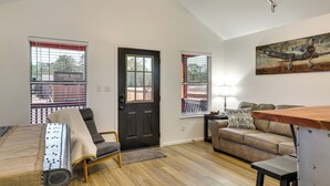 A modern living room with a sofa, a wooden table, and a painting on the wall. - 3 Mi to Sabine River! Modern Cabin Retreat (Joaquin)