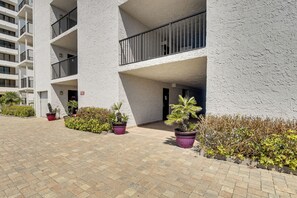 A multi-story building with balconies, potted plants, and a paved walkway. - Sleek, Oceanfront Unit in Daytona Beach Shores! (Daytona Beach Shores)