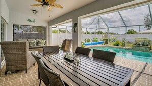 A covered patio with a pool, wicker furniture, and a ceiling fan. - Cape Coral Family Home w/ Heated Pool (Cape Coral)