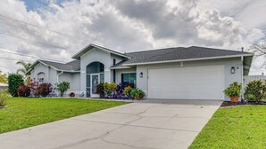 A residential house with a garage, a driveway, and landscaped garden. - Cape Coral Family Home w/ Heated Pool (Cape Coral)