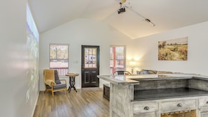 A spacious room with a wooden floor, a large window with blinds, a door, and a wall-mounted projector. - Fish, Explore & Unwind: Couple's Cabin in Joaquin (Joaquin)