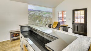 A modern kitchen with a large island, a dining area, and a view of a mountainous landscape. - Fish, Explore & Unwind: Couple's Cabin in Joaquin (Joaquin)
