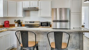A modern kitchen with white cabinets, stainless steel appliances, and a central island with two chairs. - Fish, Explore & Unwind: Couple's Cabin in Joaquin (Joaquin)