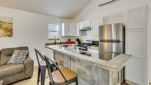 A modern kitchen with white cabinets, a stainless steel refrigerator, and a central island with bar stools. - Fish, Explore & Unwind: Couple's Cabin in Joaquin (Joaquin)