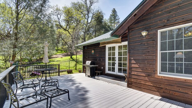 Une terrasse en bois avec des meubles d’extérieur, un barbecue et une table de patio.