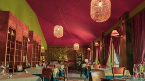 L’intérieur d’un restaurant, avec des tables, des chaises, des lampes en osier suspendues et un sol à carreaux.