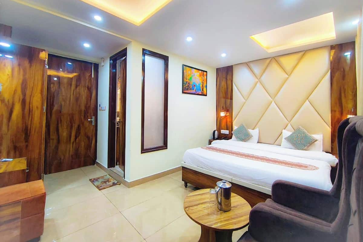 A hotel room with a bed, a round wooden table, a chair, a nightstand, and a wall-mounted artwork.