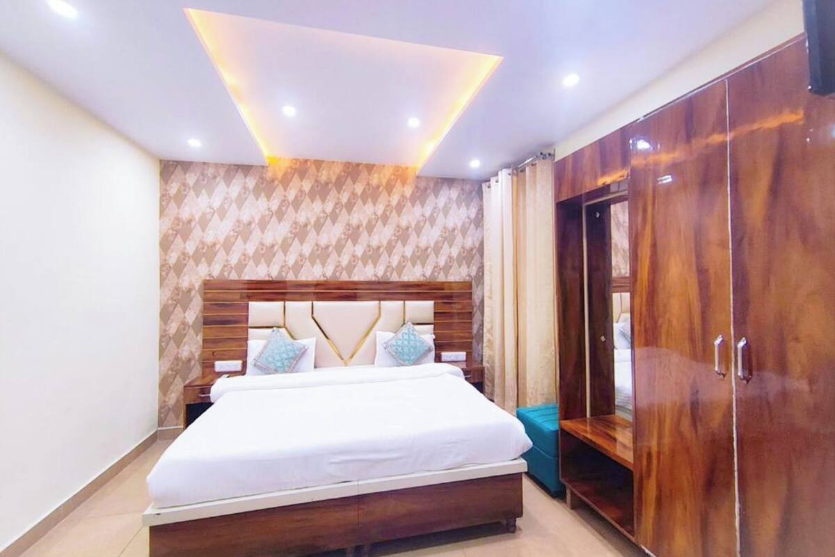 A bedroom with a bed, wooden wardrobe, and patterned wallpaper.