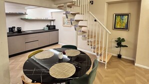 Un espace repas comprenant une table ronde, des chaises et un escalier menant à un niveau supérieur.