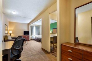 A hotel room with a bed, desk, chair, TV, dresser, and a mirror. - 1 Queen Bed | Suite, Non-Smoking, Kitchen (Florence)