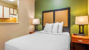 A hotel room with a bed, two bedside tables with lamps, a mirror, and a green accent wall.