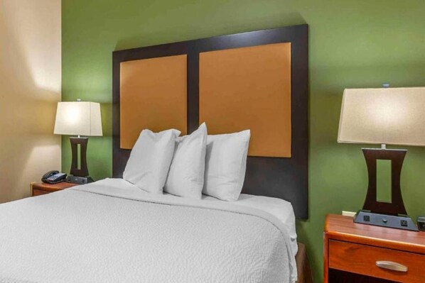 A hotel room with a bed, two bedside tables, a lamp on each table, and a phone on one of the tables. - 1 Queen Bed | Suite, Non-Smoking, Kitchen (Florence)