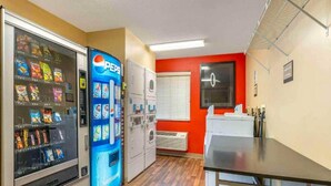 A room with a vending machine, a washing machine, and a table. - 1 Queen Bed | Suite, Non-Smoking, Kitchen (Florence)