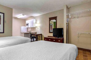 Een hotelkamer met twee bedden, een bureau met stoel, een televisie, een magnetron en een douchehoek.