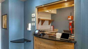 A reception desk with a computer, a fire alarm, and a sign indicating an office area.