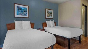 Quarto com duas camas, cabeceiras de madeira e dois quadros pendurados na parede.
