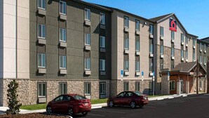 A multi-story hotel with a stone facade, multiple windows, and a parking lot with cars.