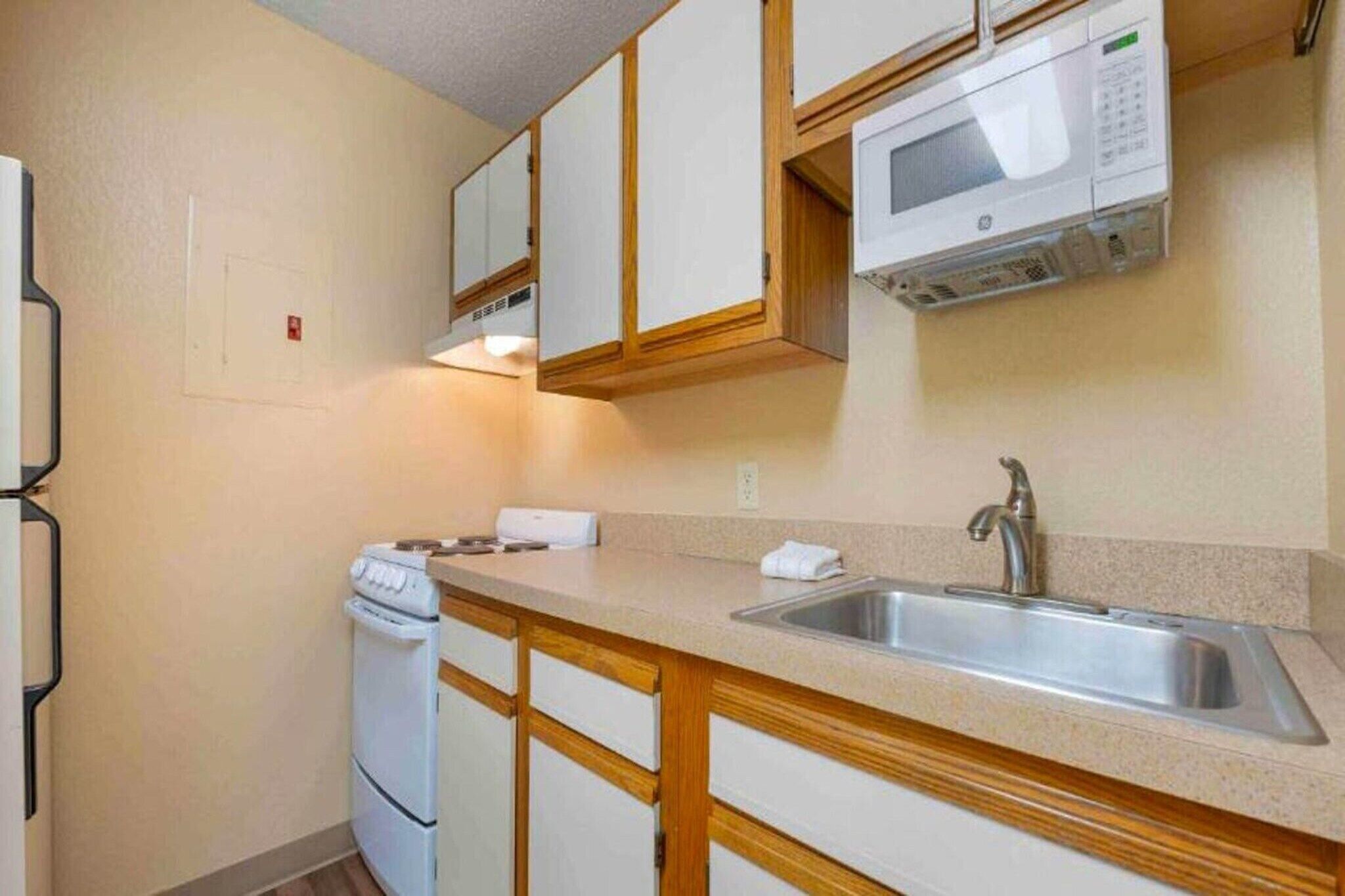 A compact kitchen with a built-in microwave, a sink, and a stove.