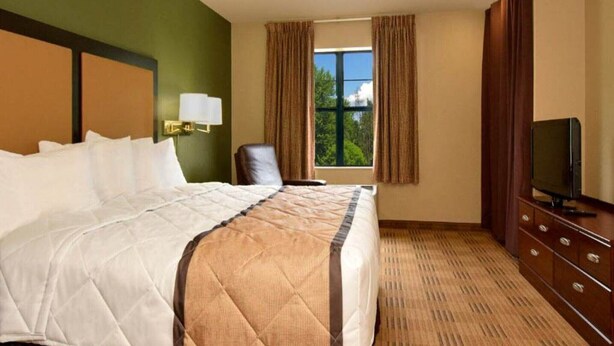A hotel room with a large bed, a television, a chair, and a window with curtains. - 1 Queen Bed | Non-Smoking, Kitchen, Sofa-Bed (Fairfield)