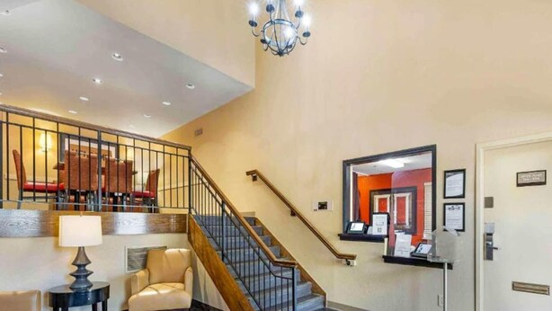 Eine Hotelhalle mit Treppe, einer Rezeption und einer Kristallleuchtre.
