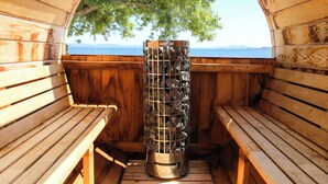 Un sauna avec des bancs en bois et un grand récipient métallique portant l’inscription « HARVIA » au centre.