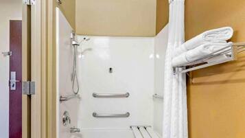 Eine Dusche mit Glastür, ein Handtuchhalter mit gefalteten Handtüchern und eine Metall-Haltestange.