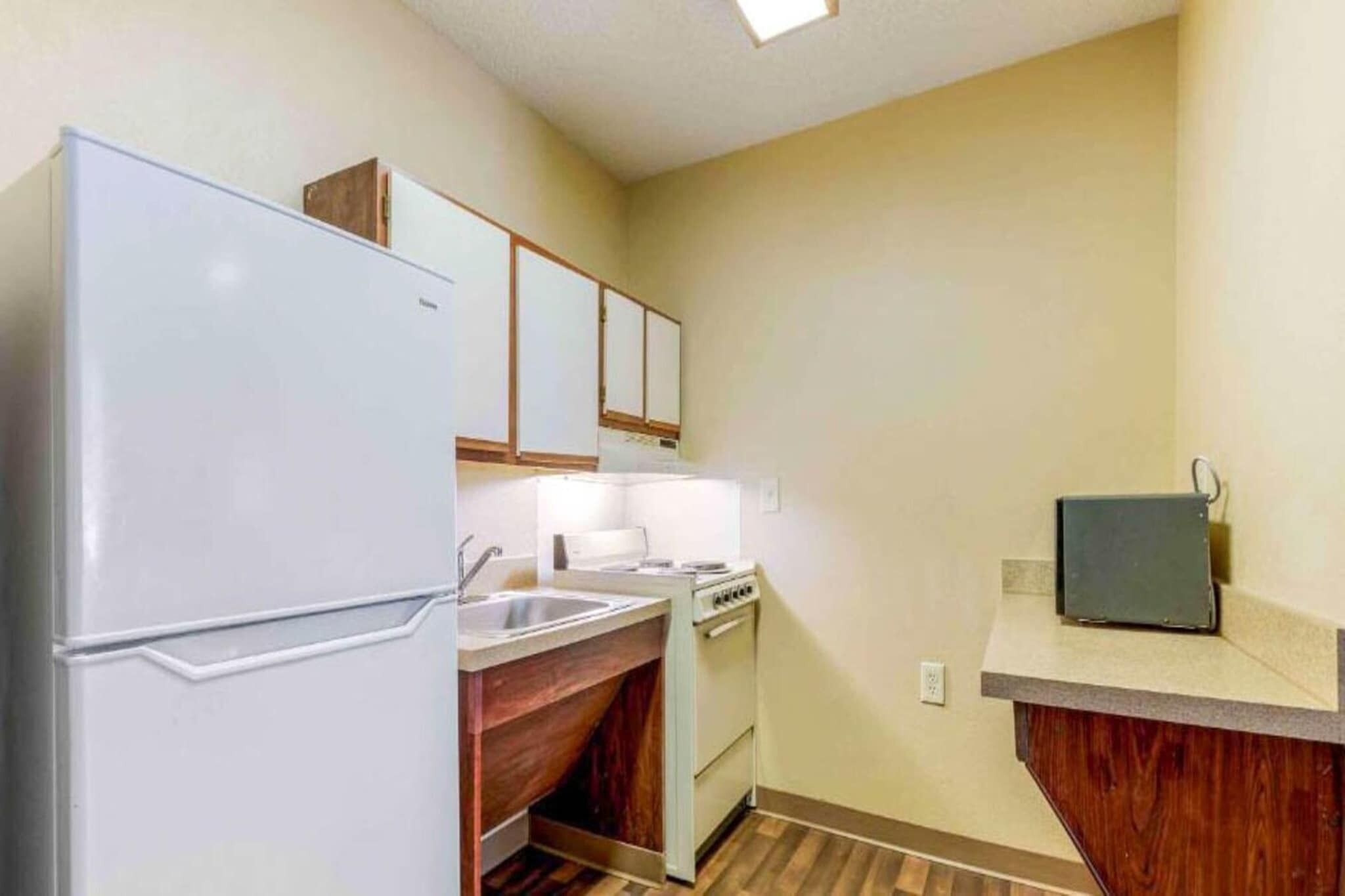 A compact kitchen with a refrigerator, sink, stove, and a small countertop.