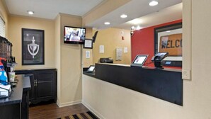 A reception area with a counter, a television mounted on the wall, a framed trophy, and a welcome sign.