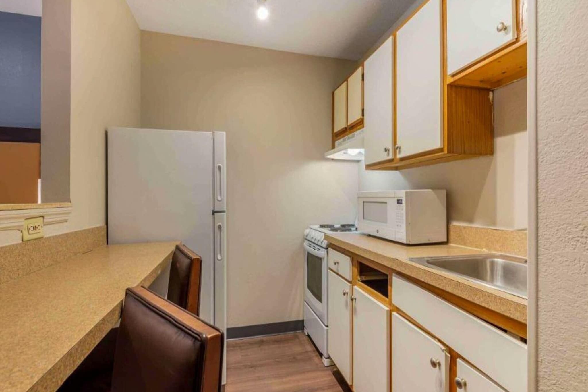 A compact kitchen with a refrigerator, stove, microwave, and a sink.