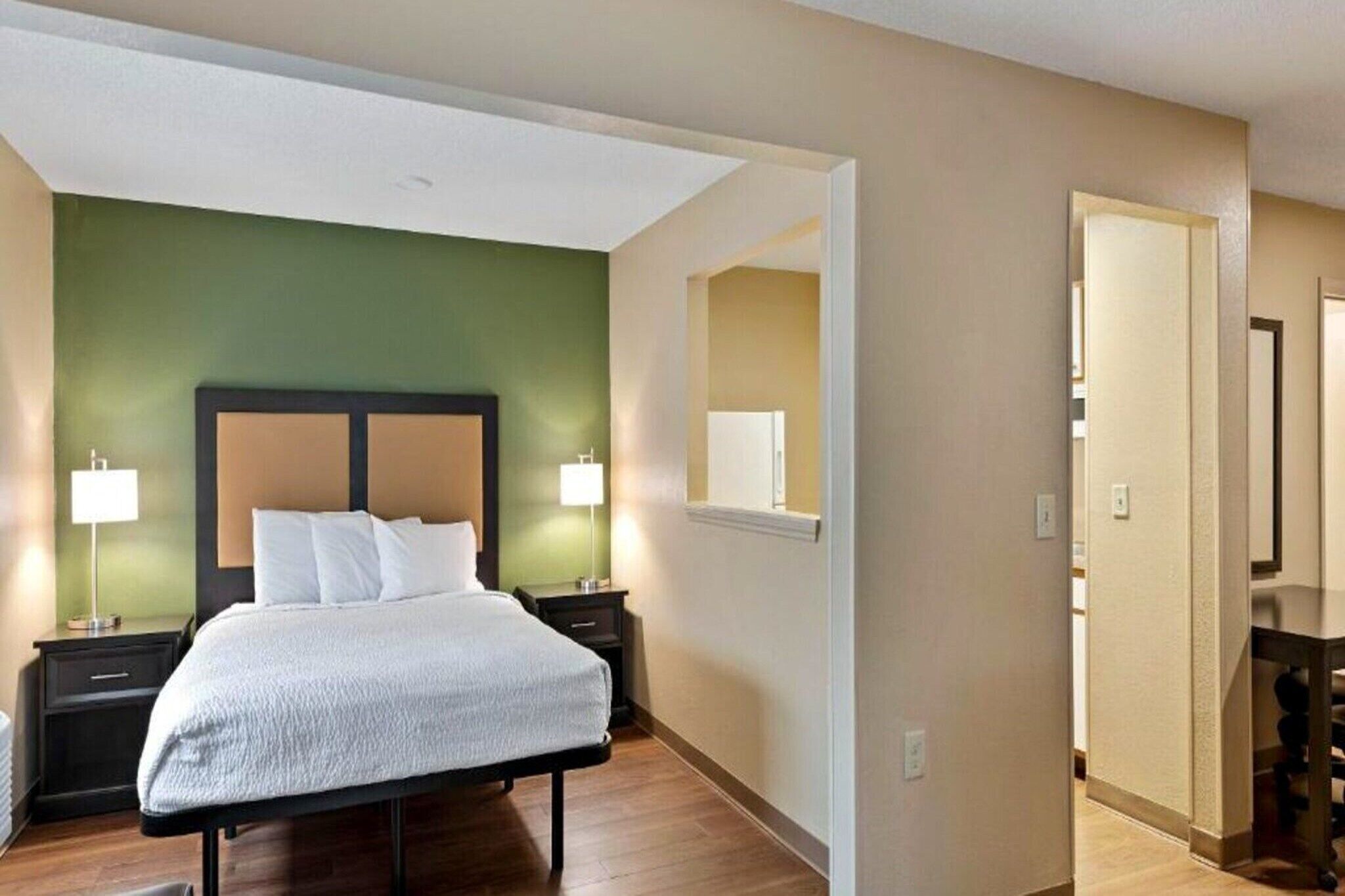A hotel room with a bed, bedside lamps, a nightstand, and a mirror.
