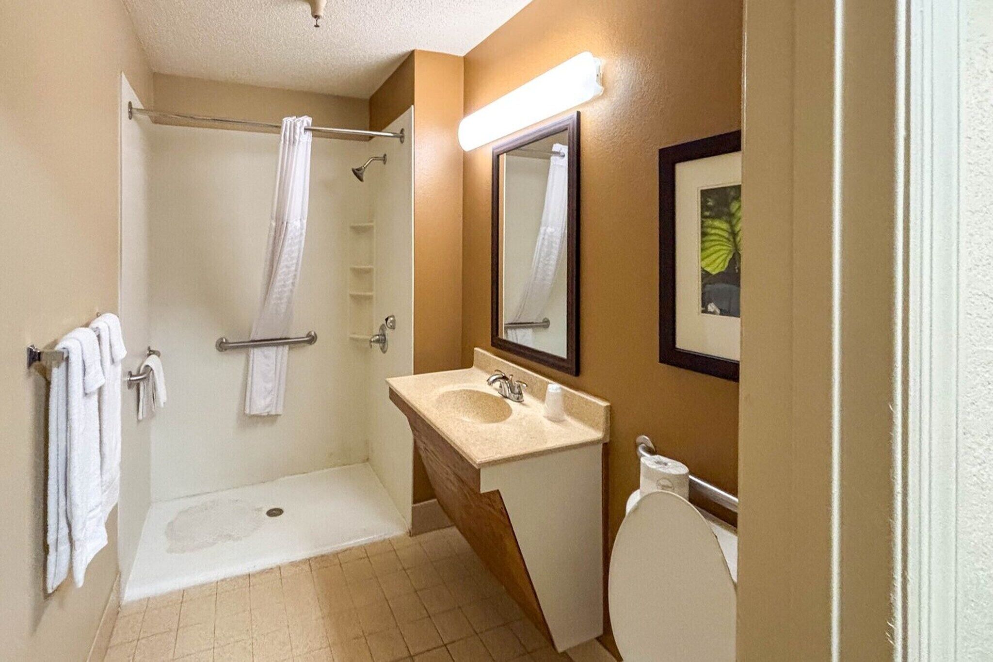 Un baño con ducha, lavamanos, inodoro y espejo.