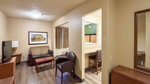 Een hotelkamer met een bank, een kleine tafel, een stoel, een bureau, een spiegel en een televisie.