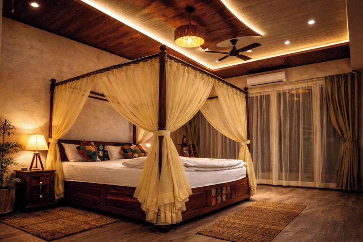 Un lit à baldaquin avec des rideaux, un ventilateur de plafond et une grande fenêtre.