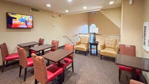 A hotel room with a TV, a staircase, and a seating area with tables and chairs. - 1 Queen Bed | Non-Smoking, Micfridge, Sofa-Bed (Greenville SC)