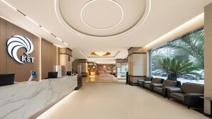 A modern hotel lobby with a reception desk, seating area, and large windows offering a view of the street. - Guizhou Fengrun Karst Hotel (Guiyang)