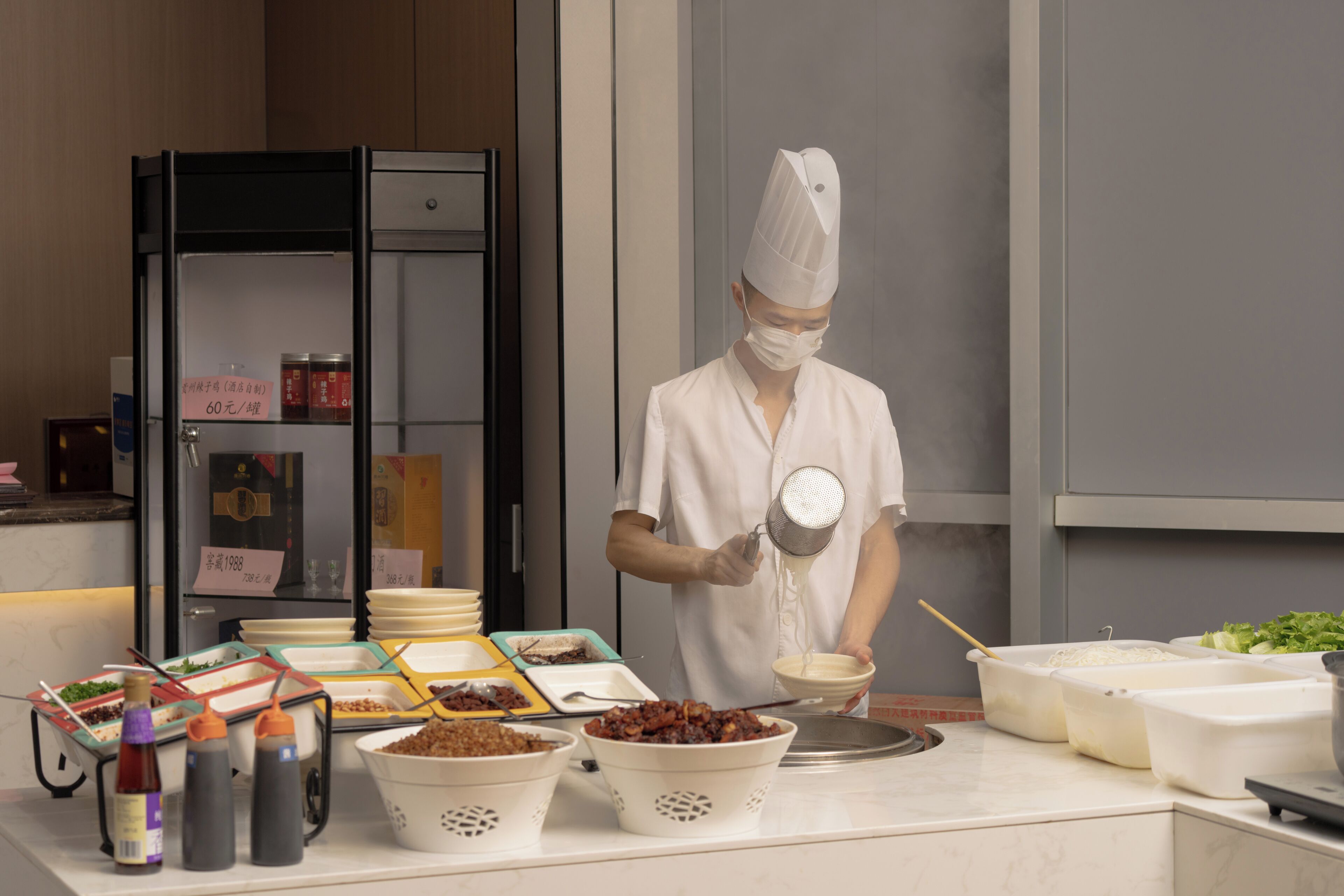 A chef preparing food in a kitchen with various dishes and condiments on the counter.