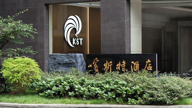 A building with a modern entrance, a logo with the letters 'KST' and Chinese characters, and well-maintained greenery in front. - Guizhou Fengrun Karst Hotel (Guiyang)
