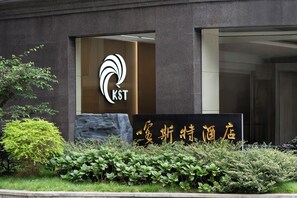 A building with a modern entrance, a logo with the letters 'KST' and Chinese characters, and well-maintained greenery in front. - Guizhou Fengrun Karst Hotel (Guiyang)