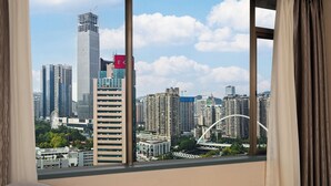 A room with a large window overlooking a cityscape with high-rise buildings and a bridge. - Guizhou Fengrun Karst Hotel (Guiyang)