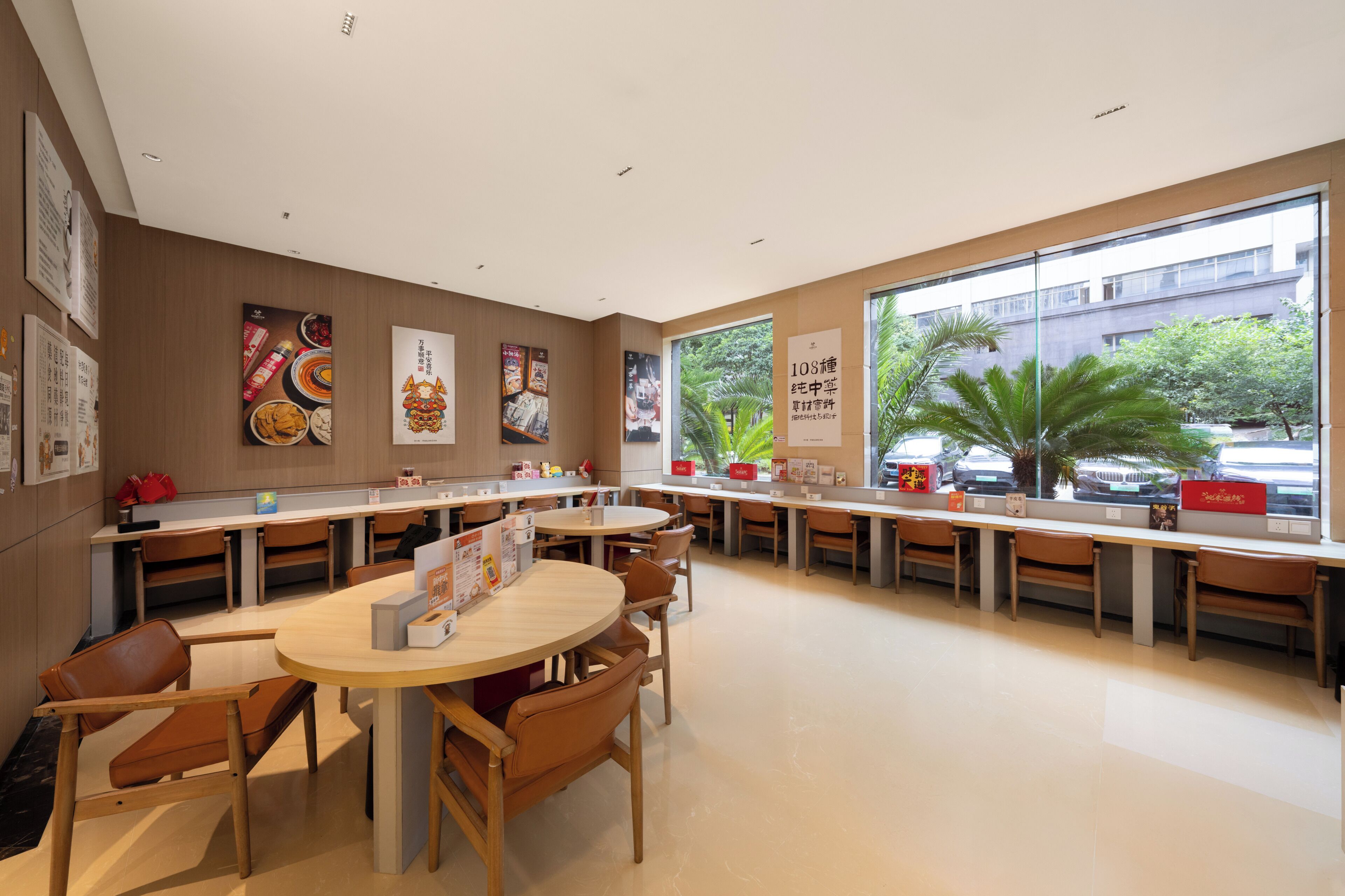 Un restaurante moderno con mesas redondas, sillas de madera y ventanas amplias que ofrecen vistas al exterior.