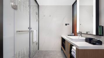 A modern bathroom with a glass shower enclosure, a large mirror, and a wooden vanity with a sink.
