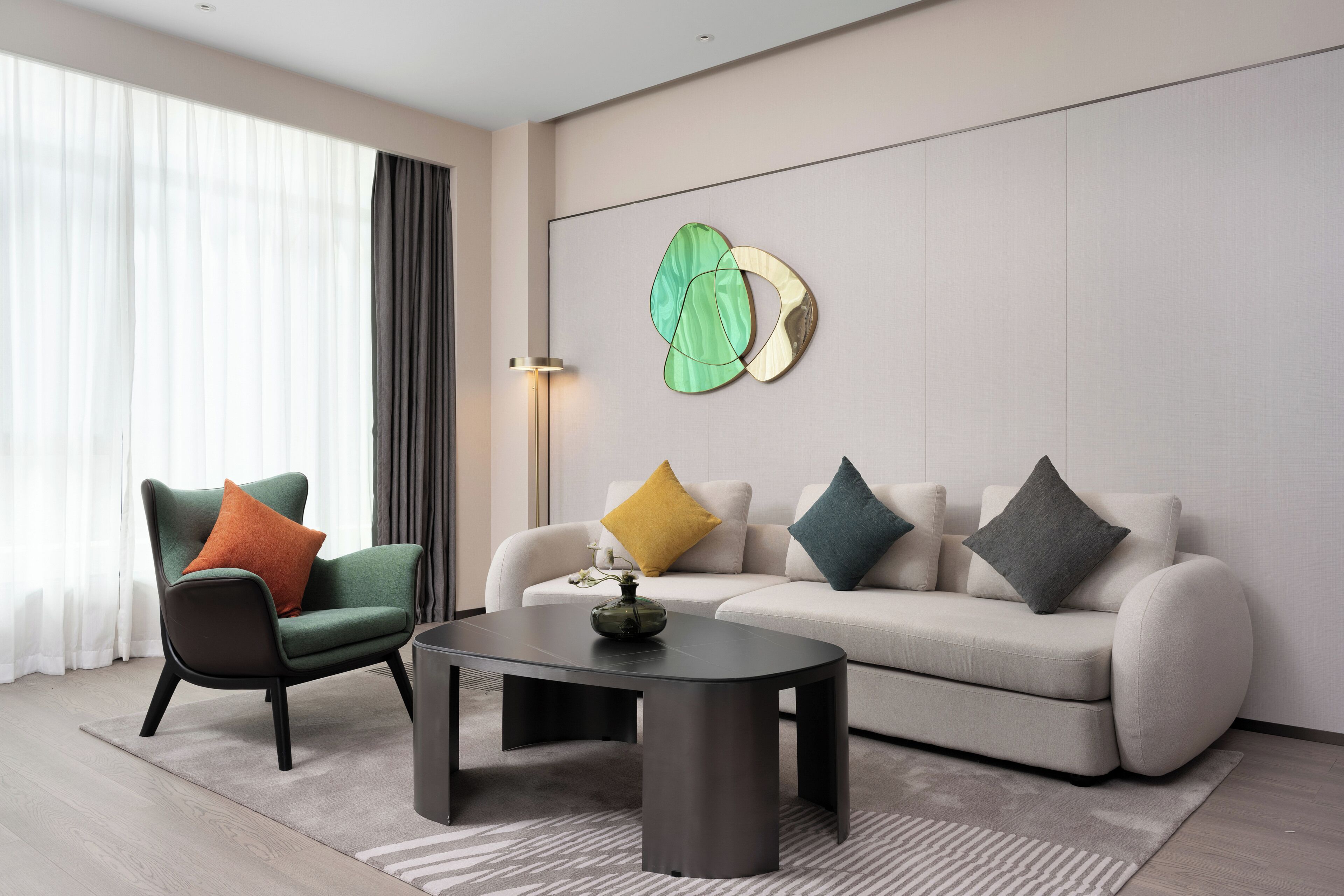 Un salon moderne comprenant un canapé, un fauteuil, une table basse et des œuvres d’art abstraites accrochées au mur.